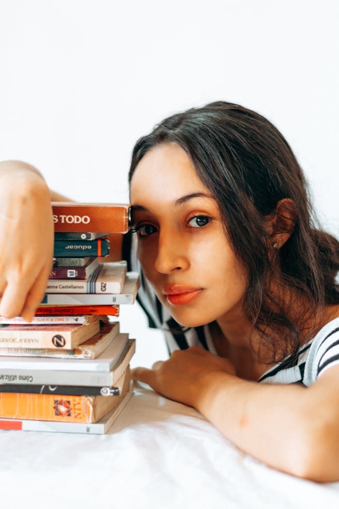 Portrait of a young woman with stacked books, embracing a love for reading and knowledge.